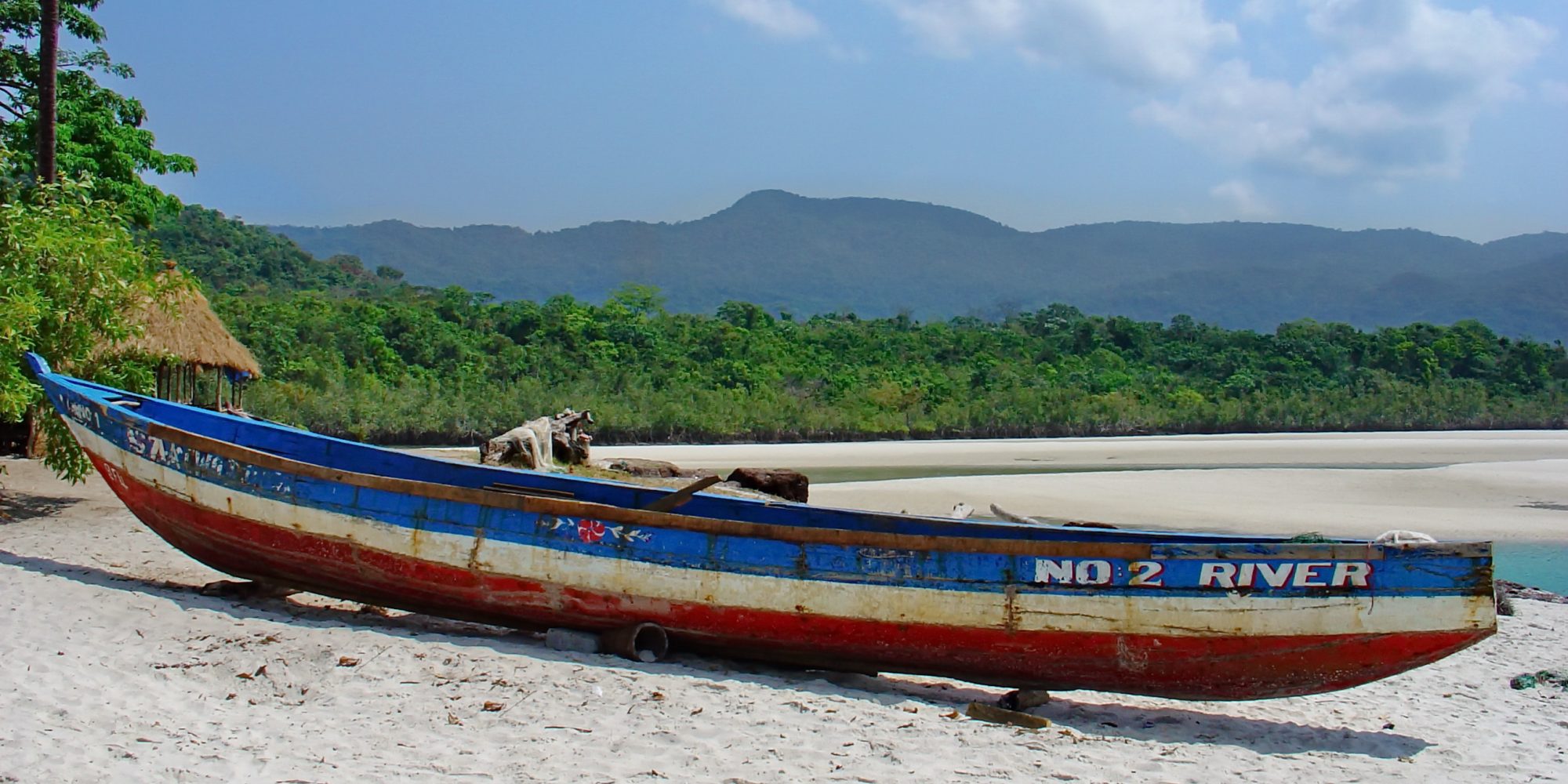 A painted fishing canoe on the white sand of No. 2 River Beach, Sierra Leone